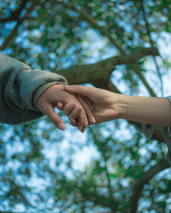 two people holding hands in front of a backdrop of foliage 